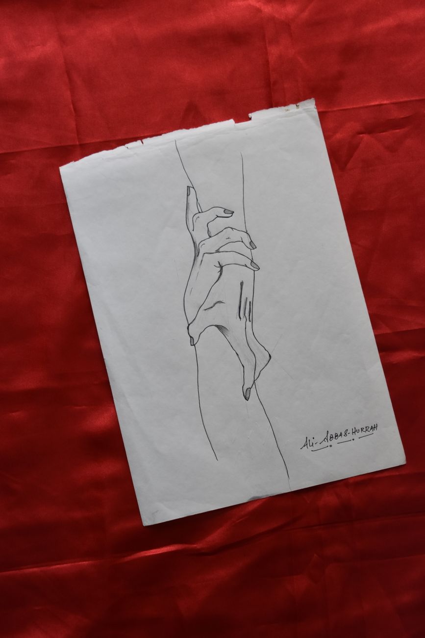 Minimalist line drawing of interlocking hands on paper against vibrant red fabric, conveying a sense of connection.