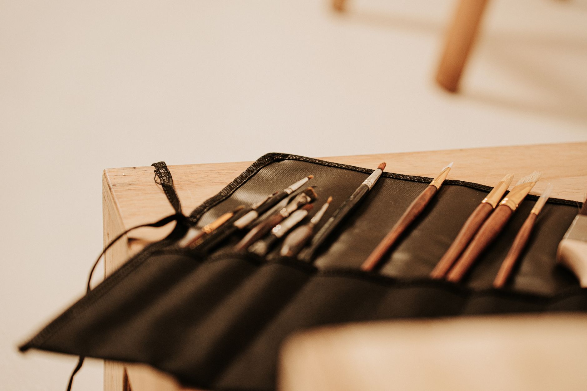 A selection of art brushes neatly arranged in a black holder on a wooden table, ideal for painting and creativity.