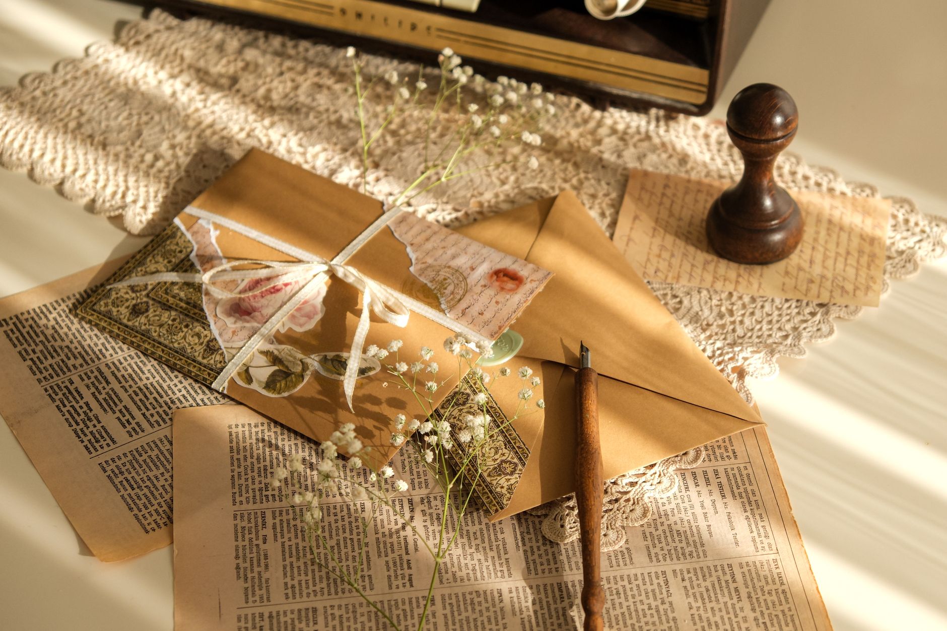Beautifully arranged vintage stationery set with envelopes, old pages, and flowers, perfect for nostalgic themes.