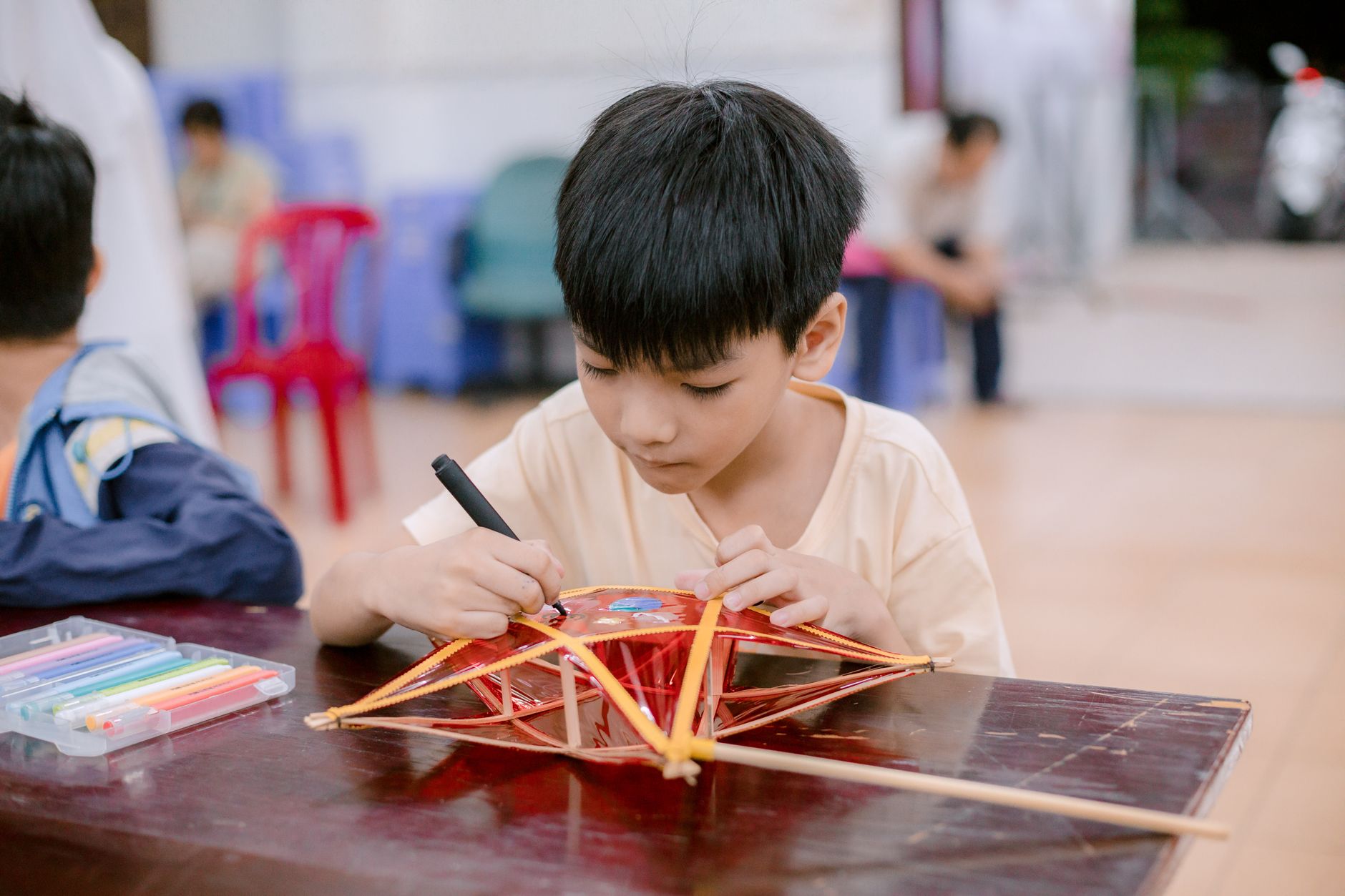 A young boy focused on decorating a traditional craft indoors. Creative and cultural activity.