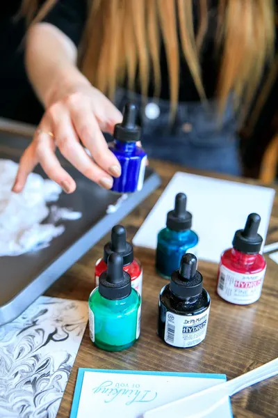 Artistic workspace with vibrant inks and tools on a wooden table, showcasing creativity.