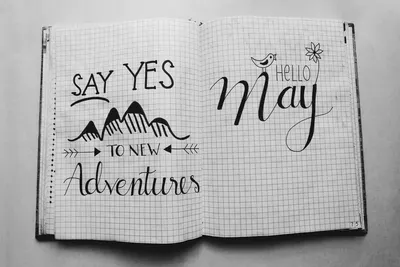 Black and white image of an open notebook featuring motivational quotes and artistic doodles.