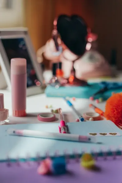 A vibrant, cluttered desk featuring colorful stationery and a heart-shaped mirror.