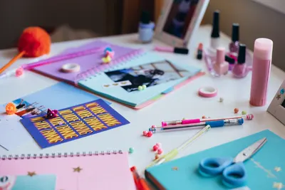 Vibrant DIY craft desk with notebooks, stationery, and colorful nail polish.