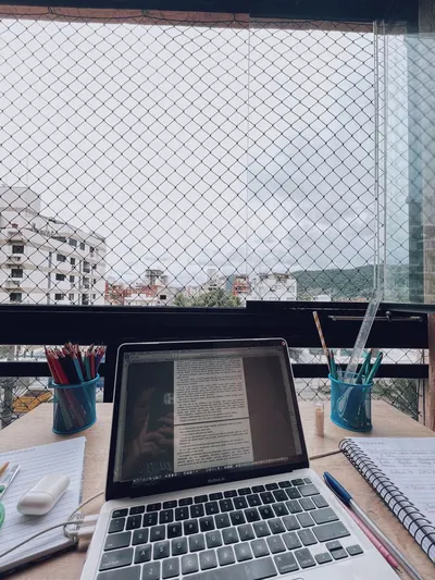 A cozy home workspace with a laptop and stationery by a window overlooking the city.