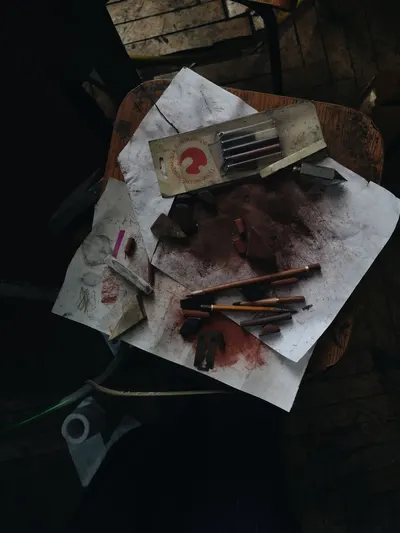Top view of a messy artist's workspace with pencils, charcoal, and paper.