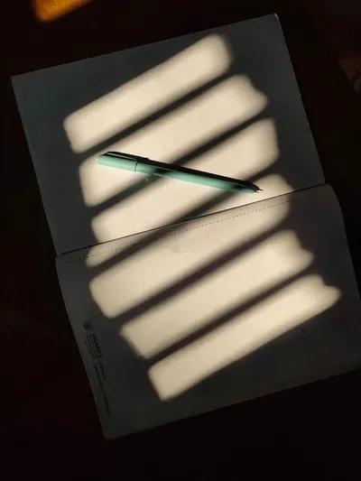 Pen on a notebook with striking light and shadow patterns, evoking a creative mood.