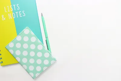 Flatlay of a polka dot wallet, pen, and notebook with copyspace on a white background.