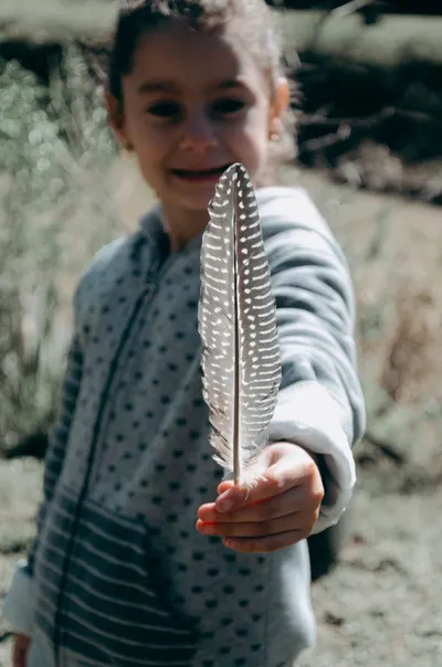 Smiling child holds a natural feather outdoors in Brazil.