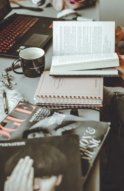 A cozy workspace with books, magazines, and a laptop, perfect for reading and studying.