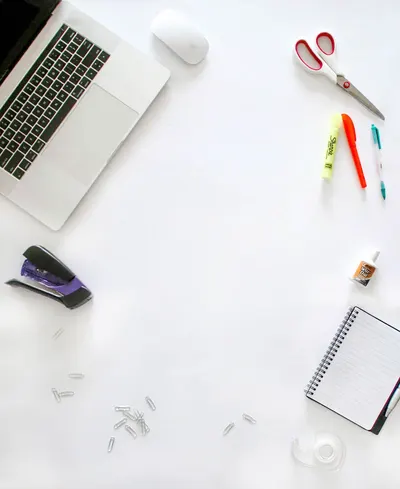 Organized office supplies on a desk including laptop, scissors, and notebook.