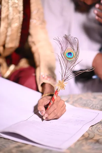 Close-up of a hand writing with a peacock feather pen in Karachi, Pakistan.