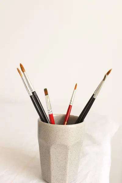 Aesthetic display of art brushes in a cup on a clean white background.