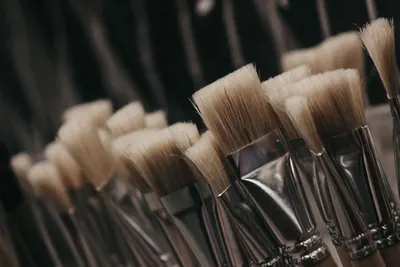 A detailed close-up shot of artist paint brushes featuring soft white bristles and metallic handles.