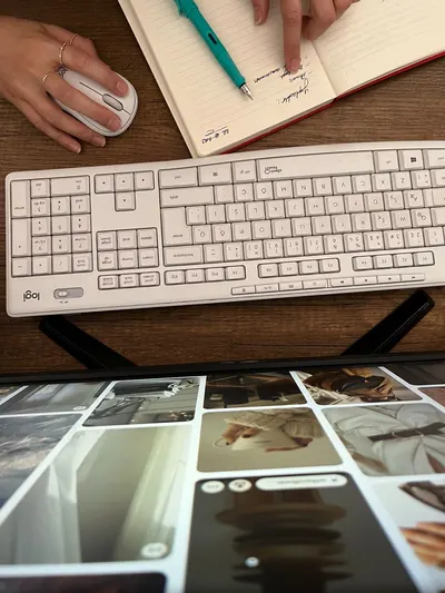 Overhead view of a workspace with keyboard, mouse, and a person planning in a notebook.
