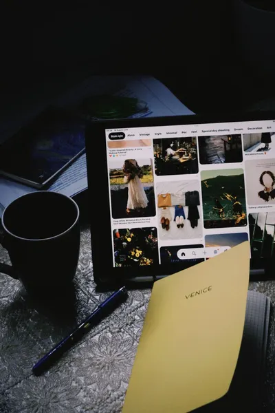 A cozy dark workspace featuring a tablet, mug, pen, and notebook labeled 'VENICE'.