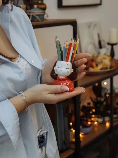 Close-up of a woman holding a handmade pencil holder with pencils indoors.