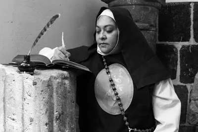 A contemplative nun writes with a quill in a serene religious setting in Mexico City.