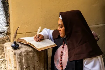 A nun writing with a quill and ink in a religious setting, symbolizing devotion and literacy.