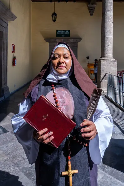 A nun holds a book and a quill in a sunlit corridor, symbolizing faith and tradition.