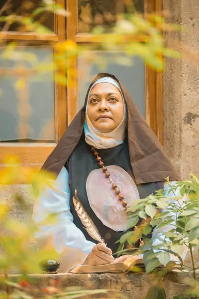 Portrait of a nun holding a quill, standing by a window in Mexico City.