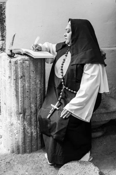 A nun in traditional habit writing by candlelight in Mexico City.