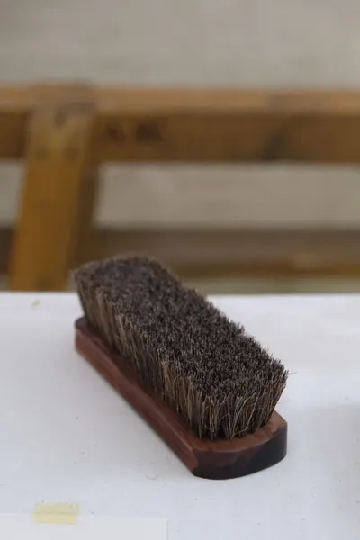 Wooden handheld brush on a table, ideal for cleaning tasks.