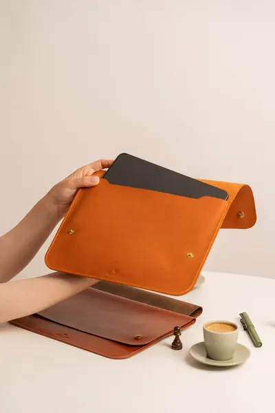 Elegant leather portfolio with a document, espresso cup, and quill pen on a table.