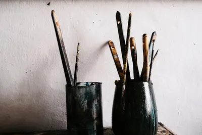 Artistic paintbrushes in vintage holders on a rustic wooden table, perfect for creative themes.