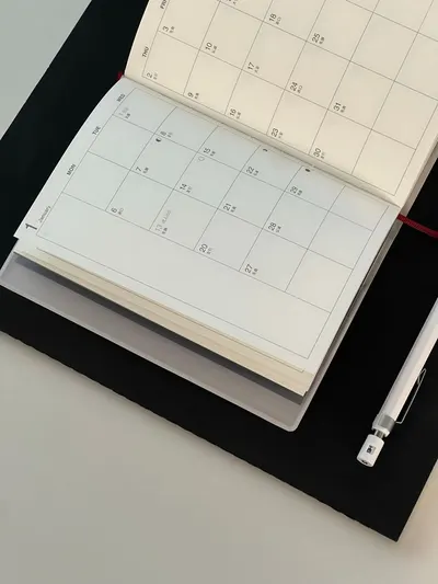 Open calendar, pen, and notebook on a desk, perfect for planning or scheduling tasks.