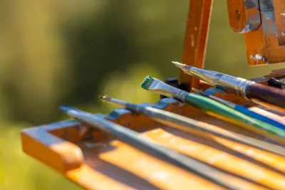 Bright close-up of paintbrushes on a wooden easel capturing an artistic moment in nature.
