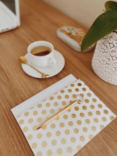 Chic home office setup with a golden dot notebook, coffee, and a decorative plant.