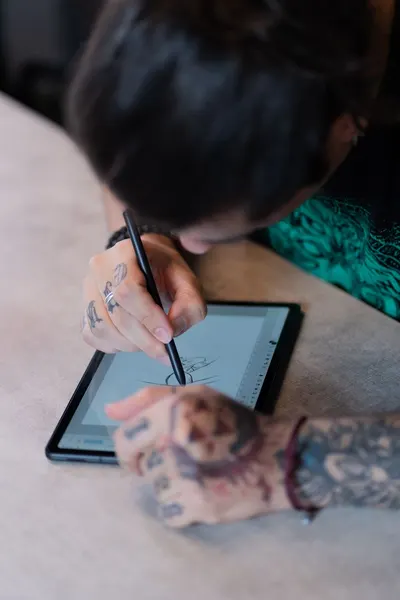 Person drawing on tablet with stylus, focusing on digital artistry.