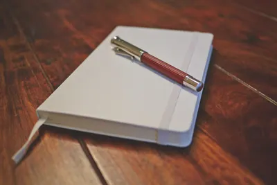Elegant setup of a notebook and pen on a wooden desk, capturing a minimalist stationery arrangement.