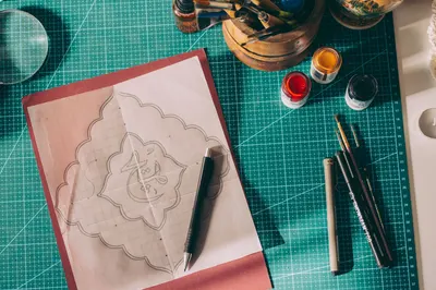 Creative workspace featuring calligraphy pens, ink, and a detailed design draft.