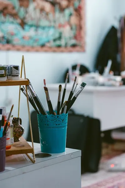 A cozy art studio with brushes in a blue container, ideal for creative inspiration.