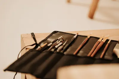 A selection of art brushes neatly arranged in a black holder on a wooden table, ideal for painting and creativity.