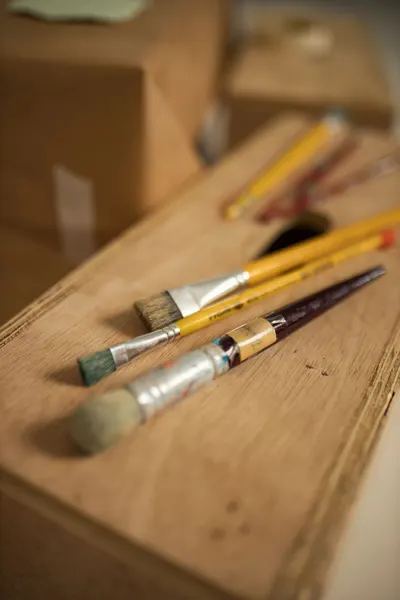 A detailed view of various paintbrushes placed on a wooden box, ideal for art and craft themes.