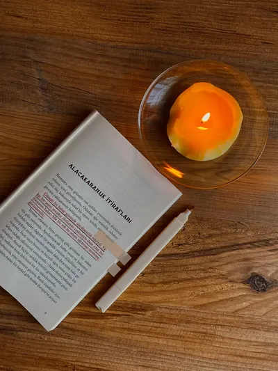Warm and inviting reading nook with an open book and a lit candle on a wooden table.