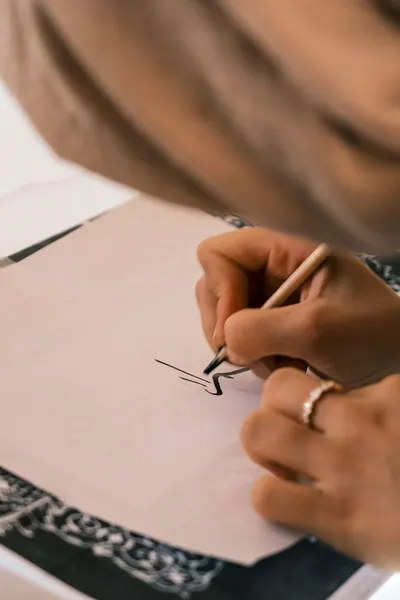 Close-up of a person practicing calligraphy on paper indoors.