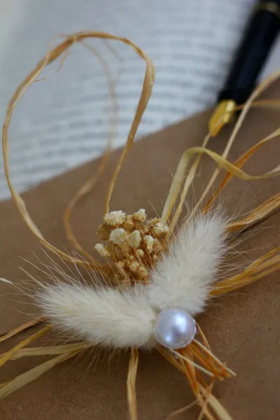A close-up of a stylish and natural composition with dried flowers and a pearl.