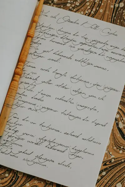 Elegant handwritten calligraphy on a notebook page with an artistic backdrop, showcasing intricate penmanship.