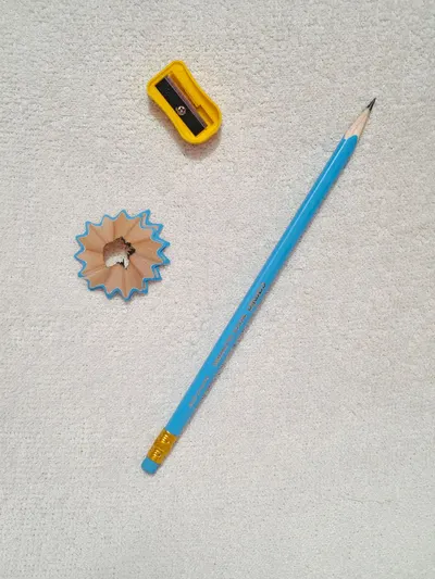 Pencil, sharpener, and shavings creatively arranged on a white background.