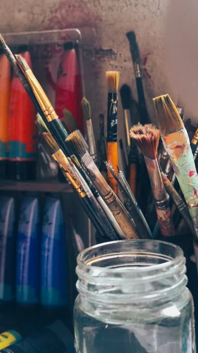 A vibrant collection of paintbrushes and acrylic paints in a creative studio setting.