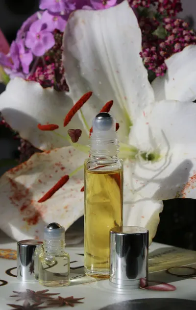 Close-up of aromatherapy roller bottles with a white lily and purple flowers for a calming effect.