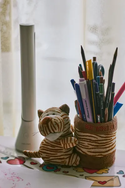 A desk with colorful stationery and a plush toy tiger, offering a warm and creative workspace vibe.