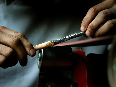 Close-up of artisan hands sharpening a tool in a Gradignan workshop, Nouvelle-Aquitaine.
