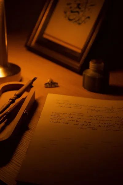 A cozy writing desk with calligraphy supplies illuminated by candlelight.