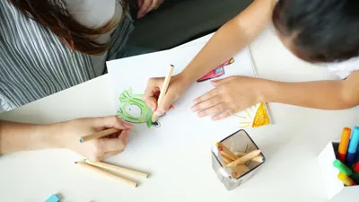 A child and adult drawing a colorful picture together, fostering creativity.