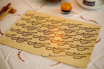 Close-up of artistic Arabic calligraphy on a paper sheet with warm tones.